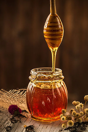 Honig, der von einem Holzlöffel in ein Glas fließt